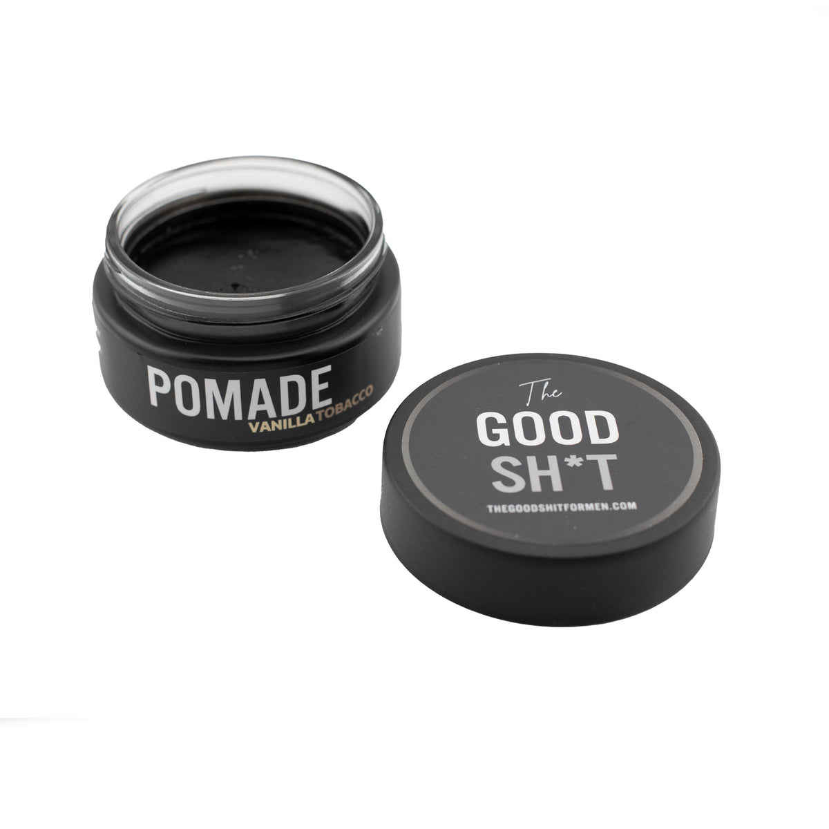A jar of The Good Sh*t Heavy Hold Pomade for men's grooming, showcasing the product's packaging and branding.