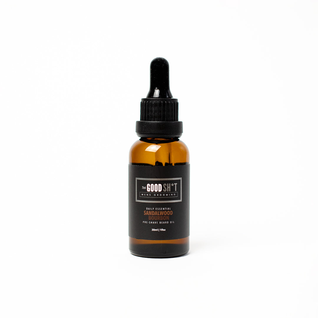 The Good Sh*t Men's Grooming pre-shave oil in sandalwood bourbon scent, 1oz, shown in a clear bottle with a black cap.